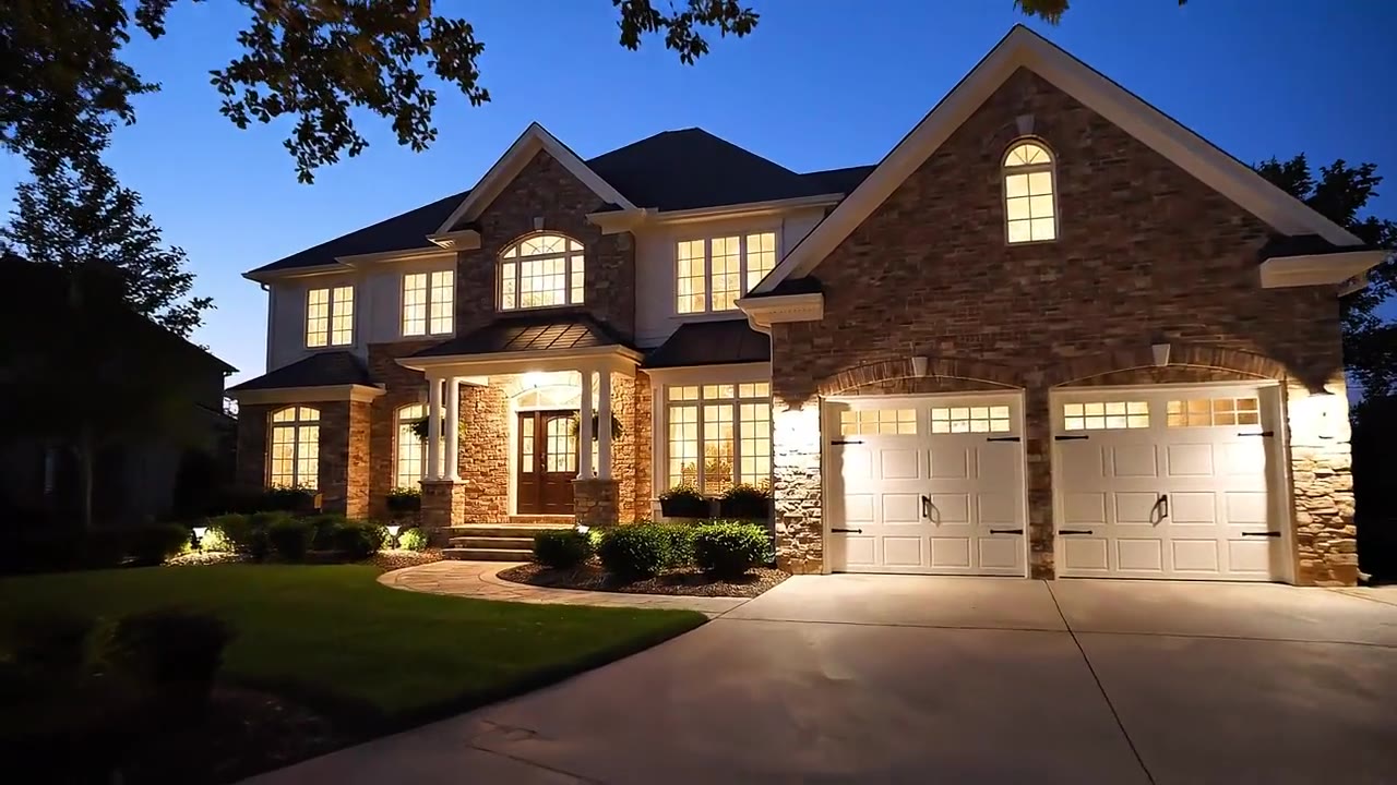 Stone-front home illuminated at twilight with landscape lighting
