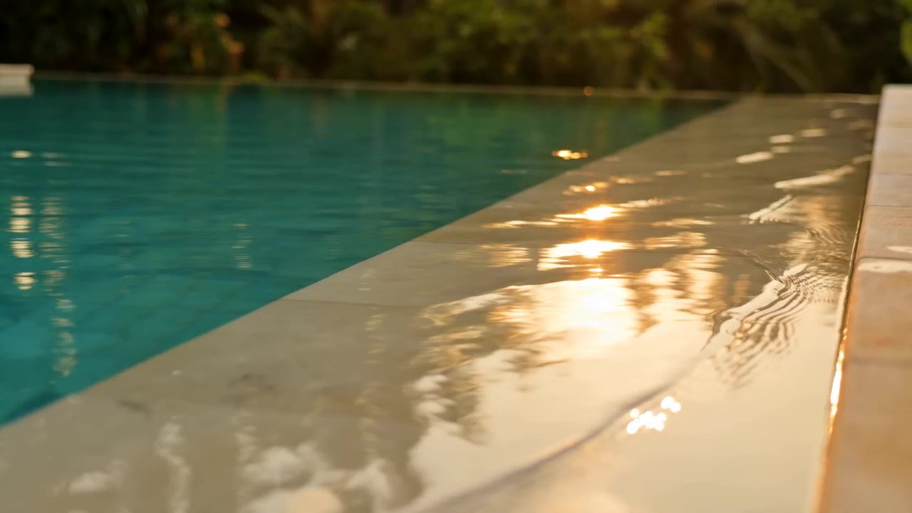 Infinity pool edge at golden hour, sun reflecting on wet stone