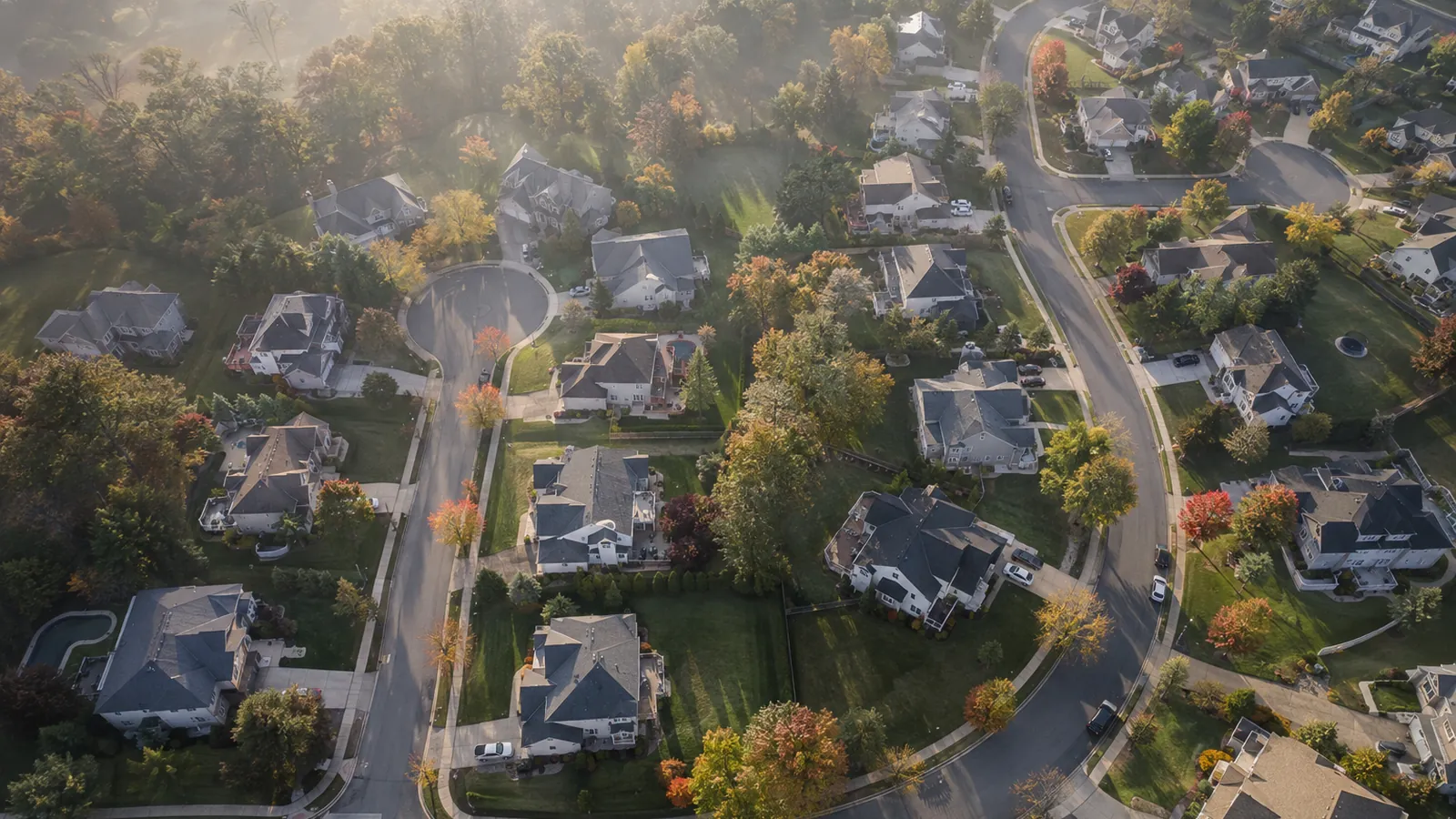 An aerial view of a suburban neighborhood of cul-de-sacs in morning haze