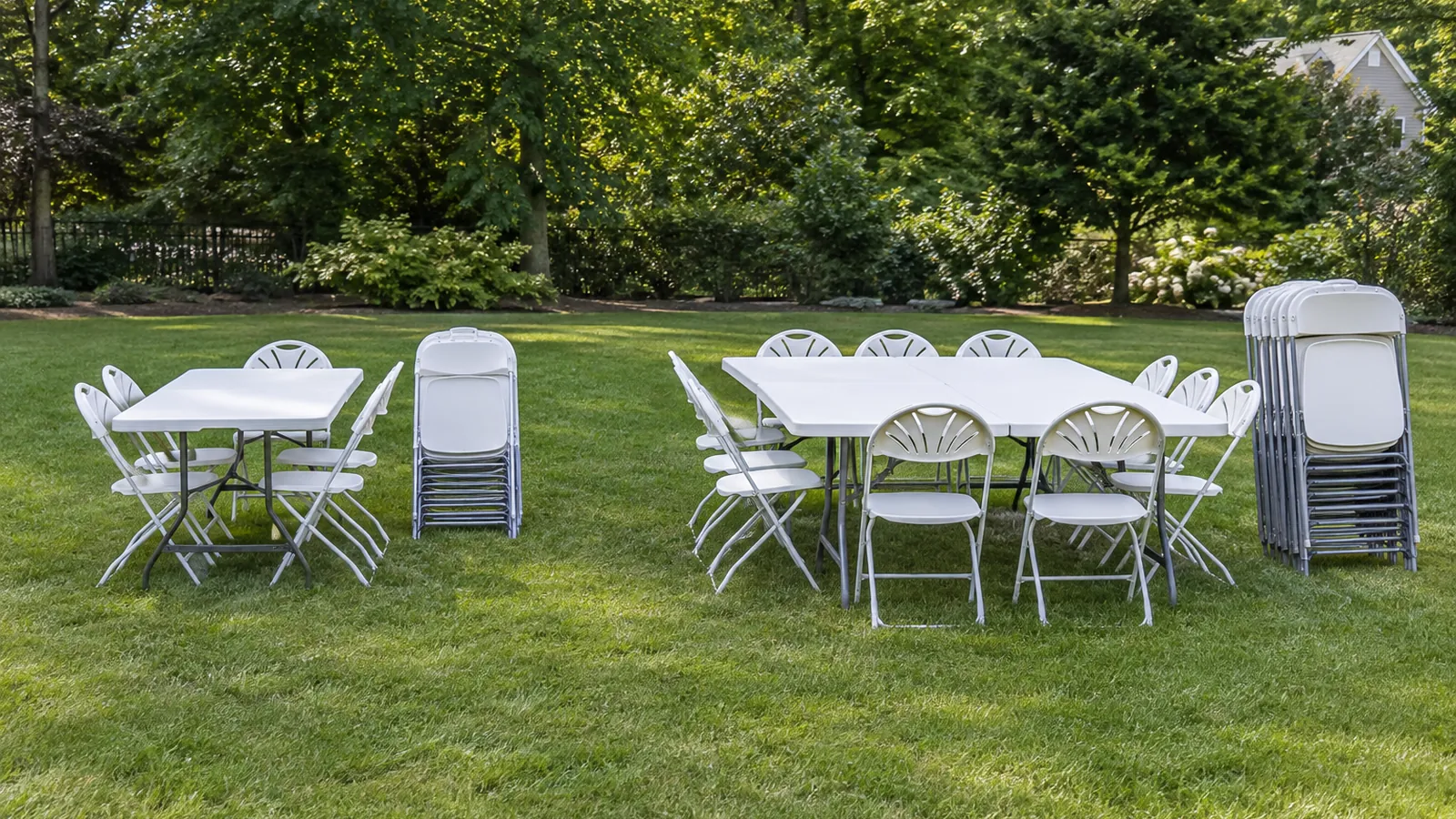 Two party rental table and chair setups of different sizes staged side by side on a lawn